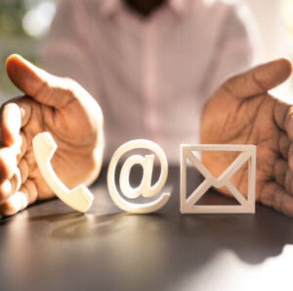 Person gesturing toward 3D icons of a phone, an at symbol, and an envelope representing contact methods.